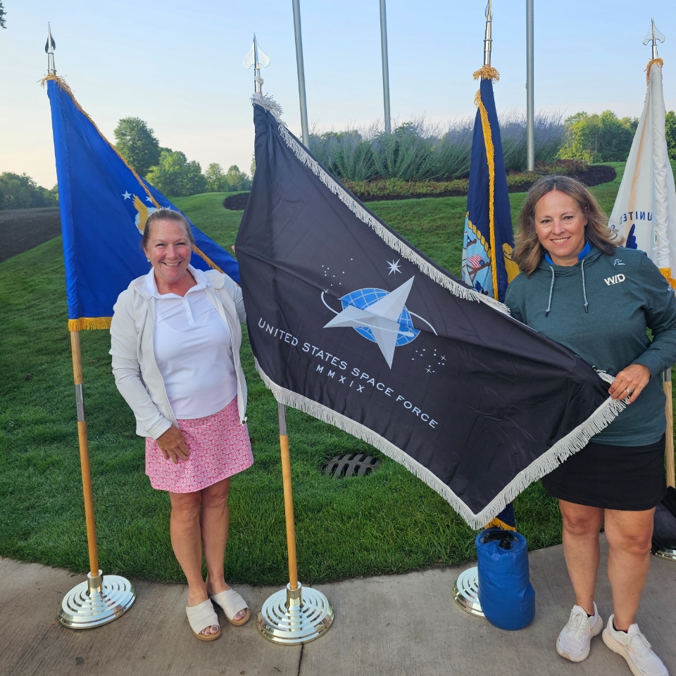Two members of Women in Defense Michigan pose with the Space Force flag